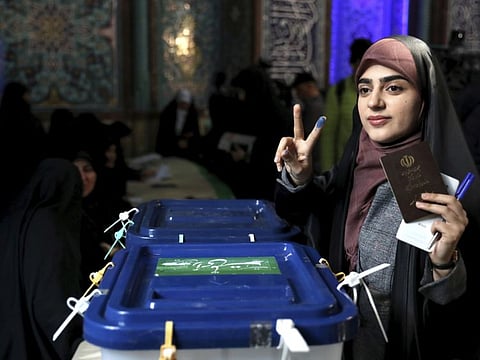 A voter flashes a victory sign with her inked finger while voting for the parliamentary elections at a polling station in Tehran.
