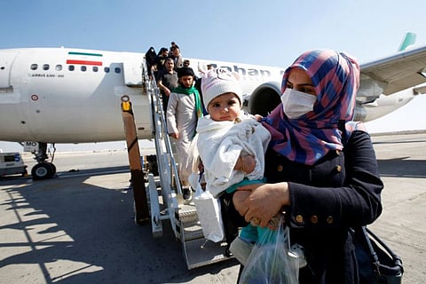 Passengers wearing protective masks disembark from a plane upon their arrival at Najaf airport, Iraq, from Iran.