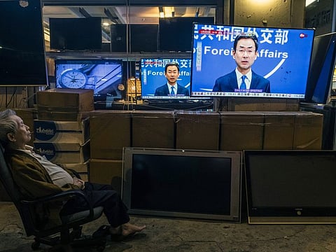A man in Hong Kong watches television coverage of Geng Shuang, a spokesman for China’s Ministry of Foreign Affairs, speaking at a news conference. Shuang on February 19 announced that China would expel three Wall Street Journal reporters working in mainland China, in a significant escalation of Beijing's pressure on foreign news media.