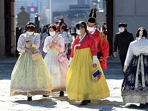 People in traditional Korean hanbok dresses wear face masks as they visit Gyeongbokgung palace in Seoul.