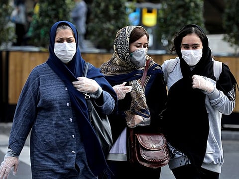 People wear masks to help guard against the Coronavirus on a street in downtown Tehran