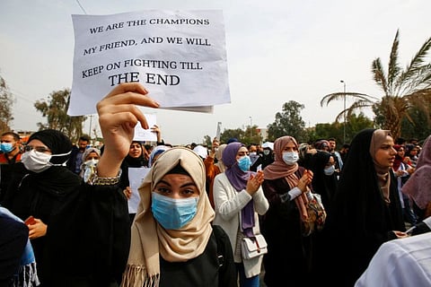 Iraqi demonstrators wear protective face masks, following the outbreak of the new coronavirus, during ongoing anti-government protests in Najaf, Iraq.