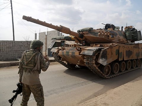 A Turkish soldier patrolling with troops in the town of Atareb in the rebel-held western countryside of Syria's Aleppo province, walks in front of an M-60T tank, part of a convoy of Turkish military vehicles on February 19, 2020