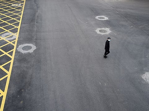 A man wearing a face mask crosses a road in Wuhan, the epicentre of the novel coronavirus outbreak, Hubei province, China February 24, 2020.