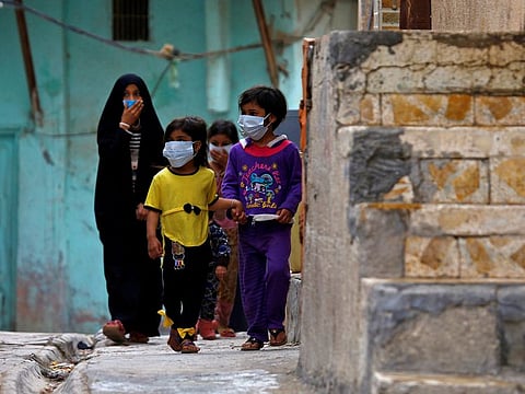 Iraqi children wear protective masks as they walk near a religious school where the first coronavirus case was detected, following the outbreak of the new coronavirus, in the holy city of Najaf.