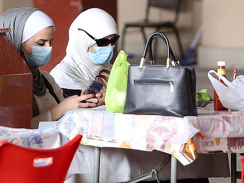 Women wear protective masks as they sit in a restaurant inside the Mubarakiya Market in Kuwait City.