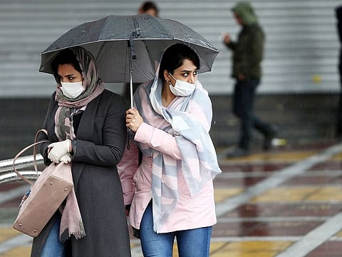 Women wear protective masks to prevent contracting coronavirus, as they walk in the street in Tehran, on Tuesday. Coronavirus outbreak is renewing doubts over the stability of the world economy.
