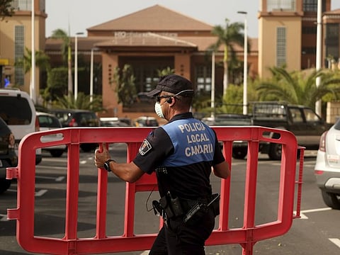 A Spanish police officer sets a barrier blocking the access to the H10 Costa Adeje Palace hotel in Tenerife, Canary Island, Spain on Tuesday. Spanish officials say a tourist hotel on the Canary Island hotel of Tenerife has been placed in quarantine after an Italian doctor staying there tested positive for a new virus from China that has infected thousands worldwide.