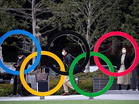 People wearing protective face masks, following an outbreak of the coronavirus, are seen next to the Olympic rings in front of the Japan Olympic Museum in Tokyo on Wednesday.