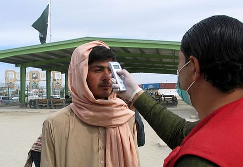 A health worker takes the temperature of a man, who returned from Afghanistan, for a medical observation as a preventive measure following the coronavirus outbreak, outside a medical camp set up near the Friendship Gate, crossing point at the Pakistan-Afghanistan border town of Chaman, Pakistan on Wednesday.