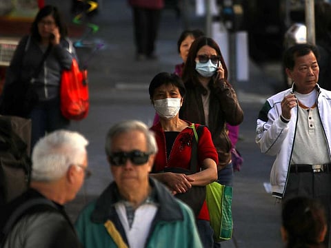 People wear surgical masks as they walk along Chinatown's Grant Avenue on February 26, 2020 in San Francisco, California.