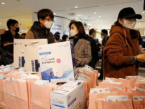 People wearing masks to prevent contracting the coronavirus wait in line to buy masks at a department store in Seoul. There are more daily cases outside China now that inside the country.