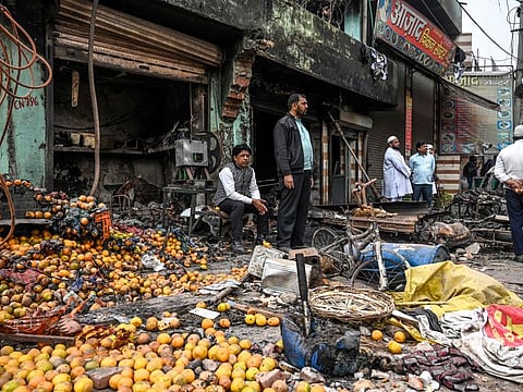 People look out near a burnt-out and damaged shop at the riot-hit area following clashes between people supporting and opposing an amendment to India's citizenship law, in New Delhi on February 27.