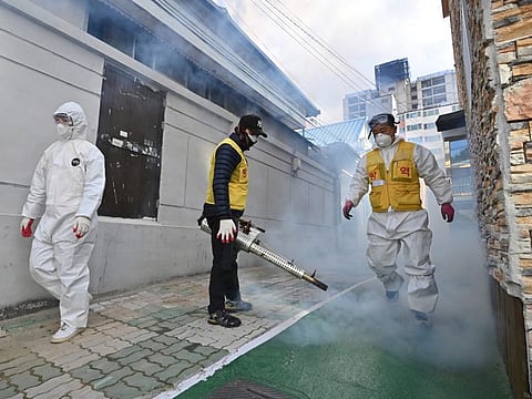 A South Korean health worker sprays disinfectant at a residential area near the Daegu branch of the Shincheonji Church of Jesus on Thursday.