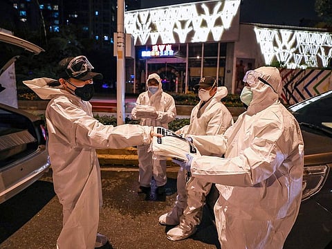 A volunteer (L) distributes protective suits to others in Wuhan in China's central Hubei province.