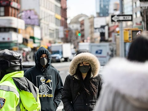 Pedestrians wear protective masks while walking along a street in New York, U.S., on Thursday, Feb. 27, 2020.