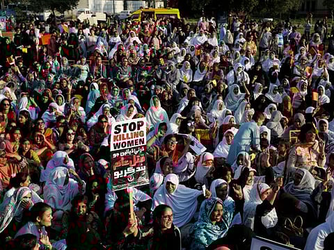 People hold signs and chant slogans as they take part in an Aurat March, or Women's March in Karachi on March 8, 2018.