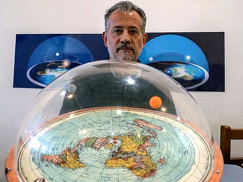 Brazilian self-avowed flat-Earth conspiracy theorist Anderson Neves holds a model of the flat earth surrounded by a dome