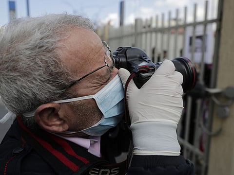 A photographer wears a medical mask and gloves as he covers ongoing protests against the Lebanese government in front of the Lebanese Ministry of Health, in Beirut February 26. Lebanon confirmed its fourth case of the disease on Friday.