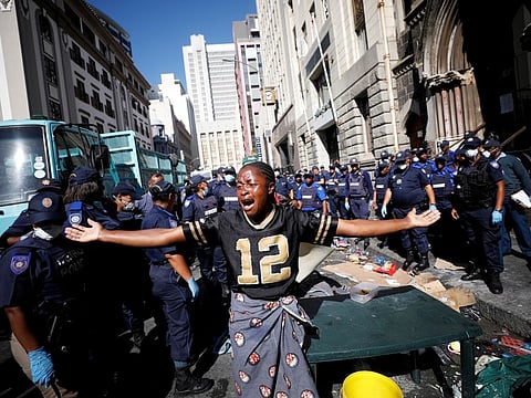 A woman wails as law enforcement officials move in to disperse a group of immigrants who had occupied a historic church and a square demanding to be moved to another country as they claimed to feel not safe because of xenophobic attacks, in central Cape Town South Africa, on Sunday.