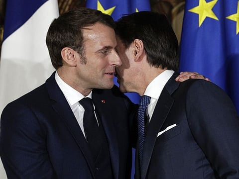 French President Emmanuel Macron, left, puts his arm around the shoulder of Italian Premier Giuseppe Conte and gives him a kiss on both cheeks during a joint press conference on the occasion of the first French-Italian summit in more than two years, in Naples, southern Italy, on Thursday.