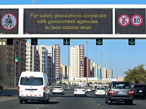 Vehicles pass by a billboard showing precautionary instructions against the coronavirus disease as they drive along a main highway in Kuwait City on March 3.