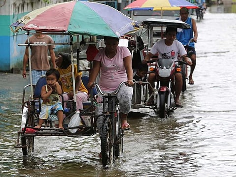 Filipinos on tricycles travel through floodwaters from overnight rains in Valenzuela City, north of Manila in 2012.