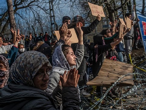 Migrants hold placards as they demonstrate, waiting at the buffer zone in front of the Pazarkule border crossing to Greece, in Edirne on March 3.