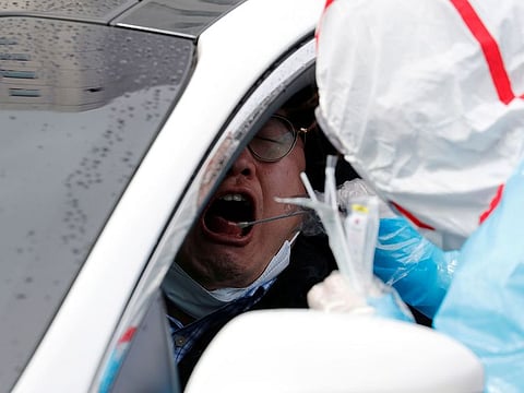 A medical staff member in protective gear uses a swab to take samples from a visitor at 'drive-thru' testing center for the novel coronavirus disease of COVID-19 in Yeungnam University Medical Center in Daegu, South Korea, March 3, 2020.