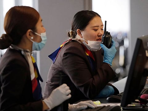 A gate agent pulls down her mask to speak on a radio at Seattle-Tacoma International Airport Tuesday, March 3, 2020, in SeaTac, Washington.