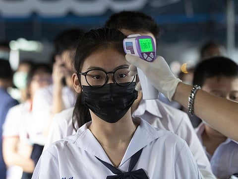 Illustrative image (Health officials in Thailand check students' temperatures before their exams)