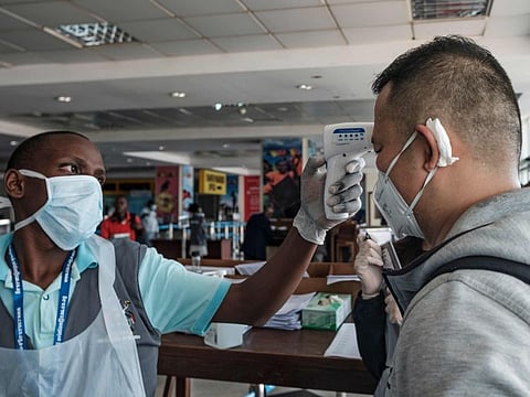A passenger originating from China has his body temparature taken upon arrival on an international flight as he waits to be screened for signs of the novel coronavirus at Entebbe Airport on March 3.