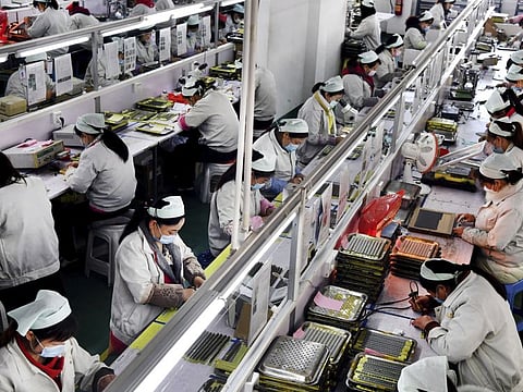 Workers wearing mask work in an electronic technology company in Mianxian County, Shaanxi province, China. Factories in China that make the world's smartphones, toys and other consumer goods are trying to protect their employees from a virus outbreak as they resume production.