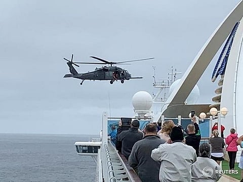 FILE PHOTO: Passengers on board the Grand Princess cruise ship, which had previously carried two passengers who contracted the coronavirus, watch while a U.S. military helicopter hovers above the deck, as they approach their original destination of San Francisco, California, U.S. March 5, 2020.