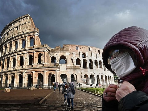 A man wearing a protective mask passes by the Coliseum in Rome on March 7, 2020 amid fear of Covid-19 epidemic.