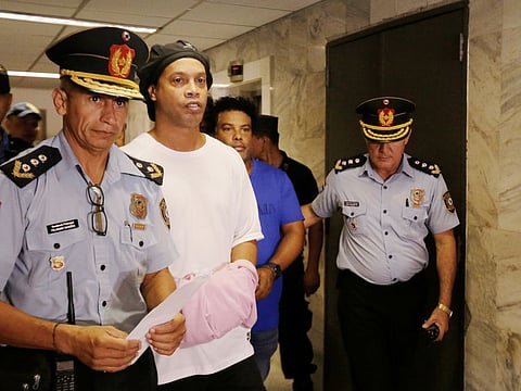 Former Brazilian football star Ronaldinho (second left) and his brother Roberto de Asis are handcuffed and escorted by police at the Supreme Court of Paraguay on Saturday.