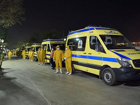 Egyptian health ministry emergency responders stand next to ambulances ready on the scene to transport suspected coronavirus disease cases that were detected on a Nile cruise ship, in the southern city of Luxor late on March 7.