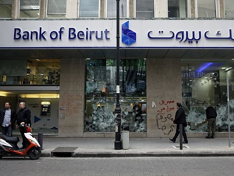 People look at the broken facade of Bank of Beirut that was smashed by anti-government protesters in Beirut, Lebanon