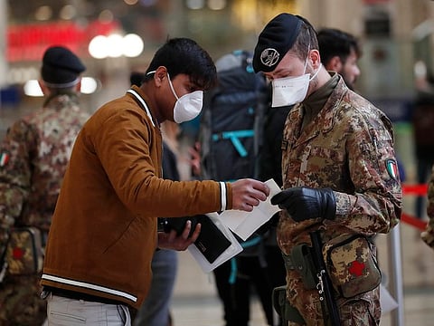 Police officers and soldiers check passengers leaving from Milan main train station, Italy, Monday, March 9, 2020.