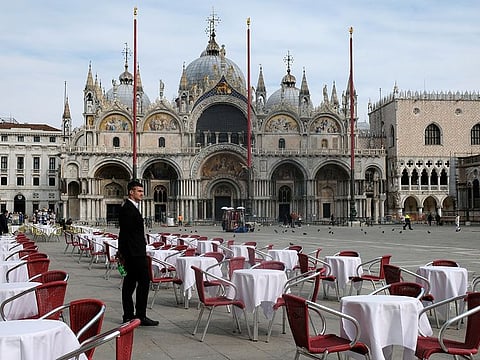 The streets are emptying... a waiter stands by empty tables outside a restaurant at St. Mark's Square after the Italian government imposed a virtual lockdown to contain the coronavirus outbreak. Key sectors of the global economy are in turmoil and could set off a deep recession.