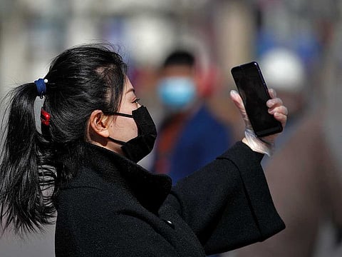 A masked woman wearing a hand glove takes a selfie at the Wangfujing shopping district in Beijing, Tuesday, March 10, 2020. For most people, the new coronavirus causes only mild or moderate symptoms, such as fever and cough. For some, especially older adults and people with existing health problems, it can cause more severe illness, including pneumonia. (AP Photo/Andy Wong)