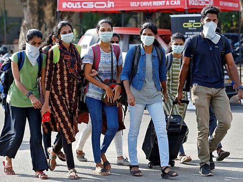 A group of students wearing protective masks walk outside a railway station amid coronavirus fears, in Kochi, on March 10, 2020.