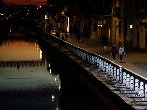 Few people walk at the Naviglio Grande canal, one of the favourite spots for night life in Milan, Italy, Tuesday, March 10, 2020.
