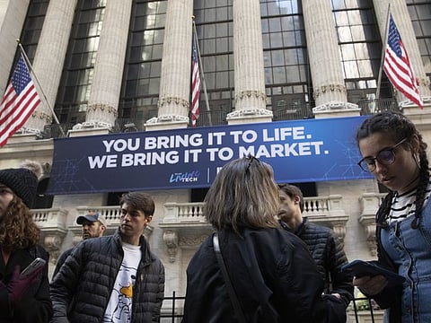 In this Monday, March 9, 2020 file photo, people stop to look at the New York Stock Exchange.