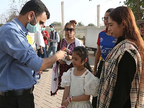 A Pakistani volunteer takes the temperature of a young spectator outside the National Stadium in Karachi, Pakistan, Thursday, March 12, 2020/file photo.