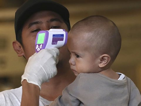 A mall officer checks visitor body temperature in Jakarta, Indonesia, Thursday, March 12, 2020