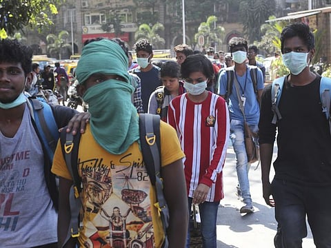 A group of tourists wearing masks walk outside a local train station in Mumbai, India, on Thursday.