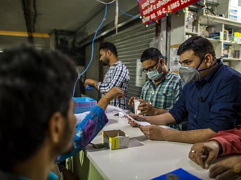 Vendors wearing protective masks serve customers at a pharmacy in New Delhi, India, on Wednesday.