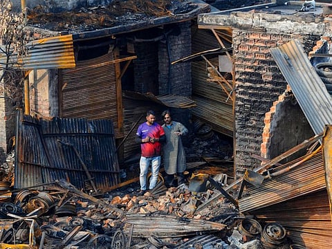 Shop owners look at the charred remains of the tyre market in riot affected Gokulpuri area of North East Delhi, Saturday, March 7, 2020. The riots were a grim reminder of the earlier happenings: Gujarat in 2002 and Delhi in 1984.