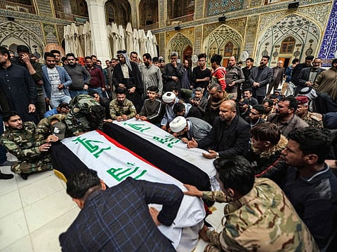 Mourners pray over coffins draped with the Iraqi national flag inside the Imam Ali Shrine in the central Iraqi holy city of Najaf on March 14, 2020, during a funeral ceremony for members of the Hashed al-Shaabi (Popular Mobilisation Forces) paramilitaries who were killed in an area targeted by US military air strikes. US air strikes targeting pro-Iranian military factions in Iraq killed one civilian and five security personnel early on March 13.